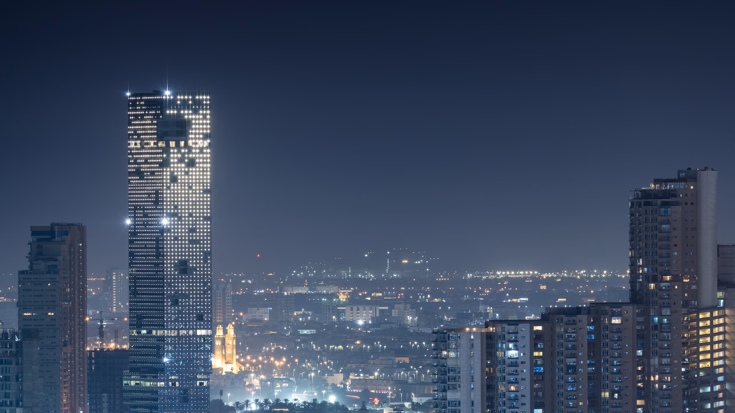 Golden Tower illuminated at night in Jeddah, Saudi Arabia, its faceted glass silhouette rising above the surrounding lower-rise cityscape