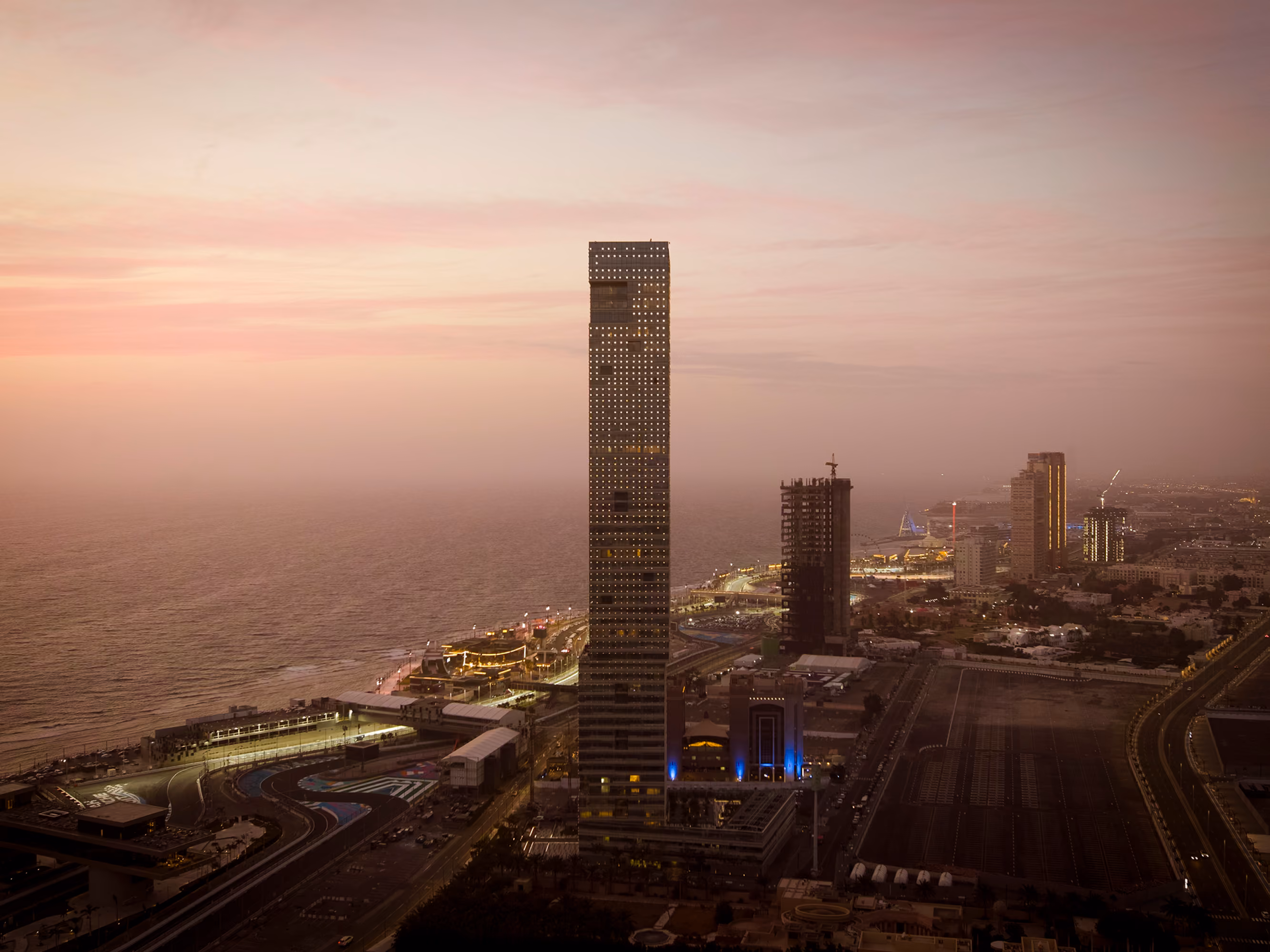 Golden Tower rising above Jeddah's seafront corniche at dusk, its illuminated silhouette towering over the coastal skyline in Saudi Arabia
