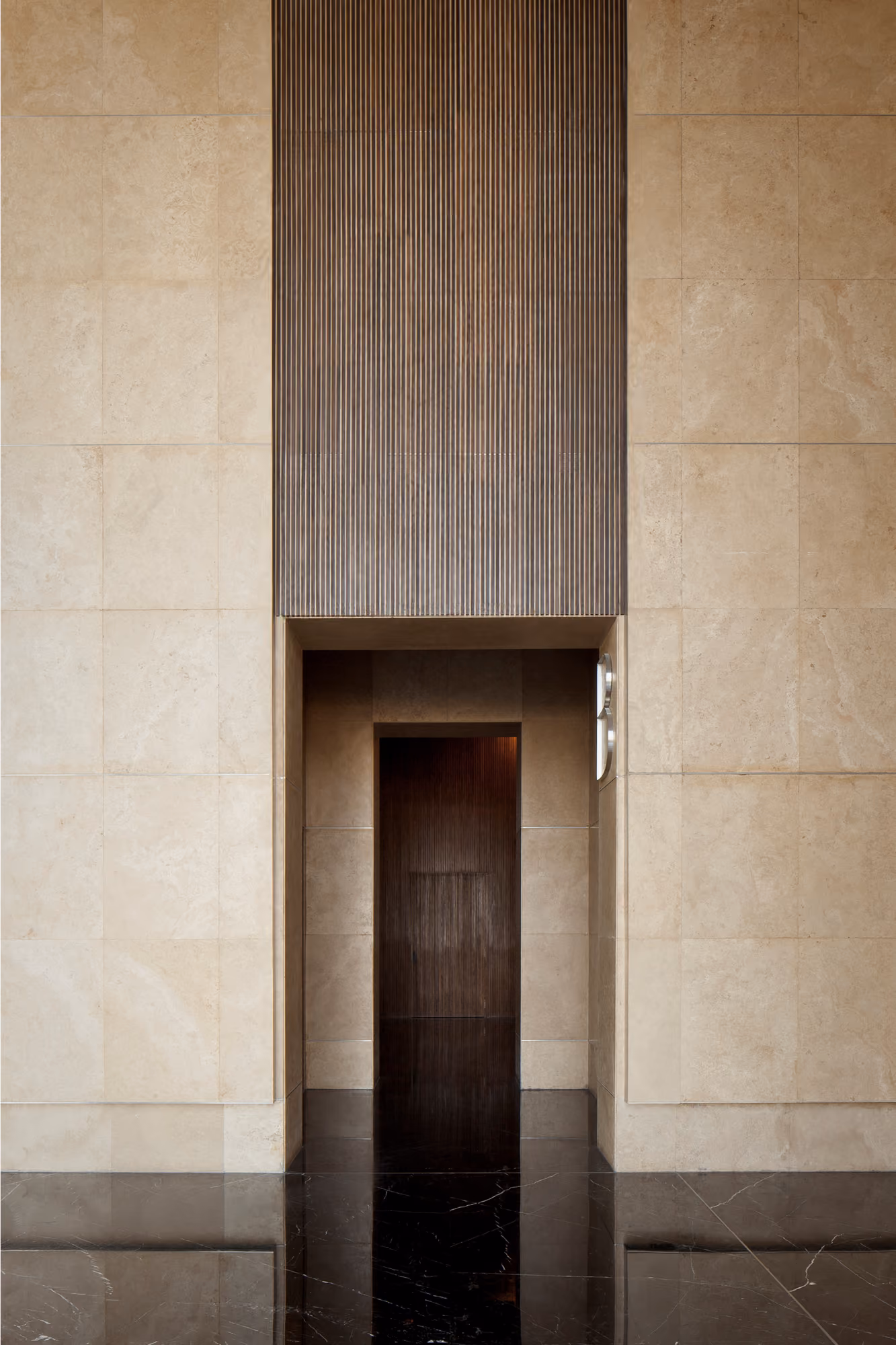 Recessed doorway at Platinum Tower in Beirut, ribbed dark wood cladding above a wood-panelled entrance set in beige stone walls with polished dark floors