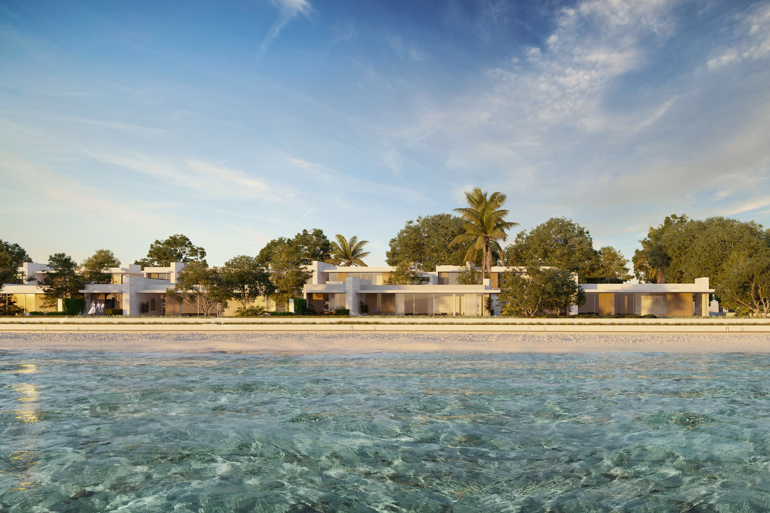 Low-rise villas of Al Zorah Shores in Ajman seen from the water, flat white facades nestled among palm trees along a sandy shoreline