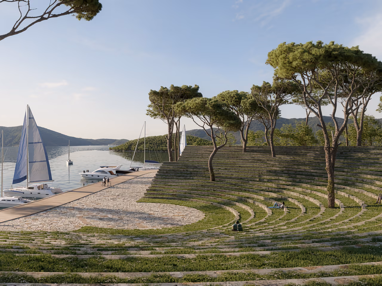 Grass-covered amphitheater steps shaded by pine trees at Tivat Hotel and Beach Resort in Tivat, overlooking a marina with sailboats on the bay