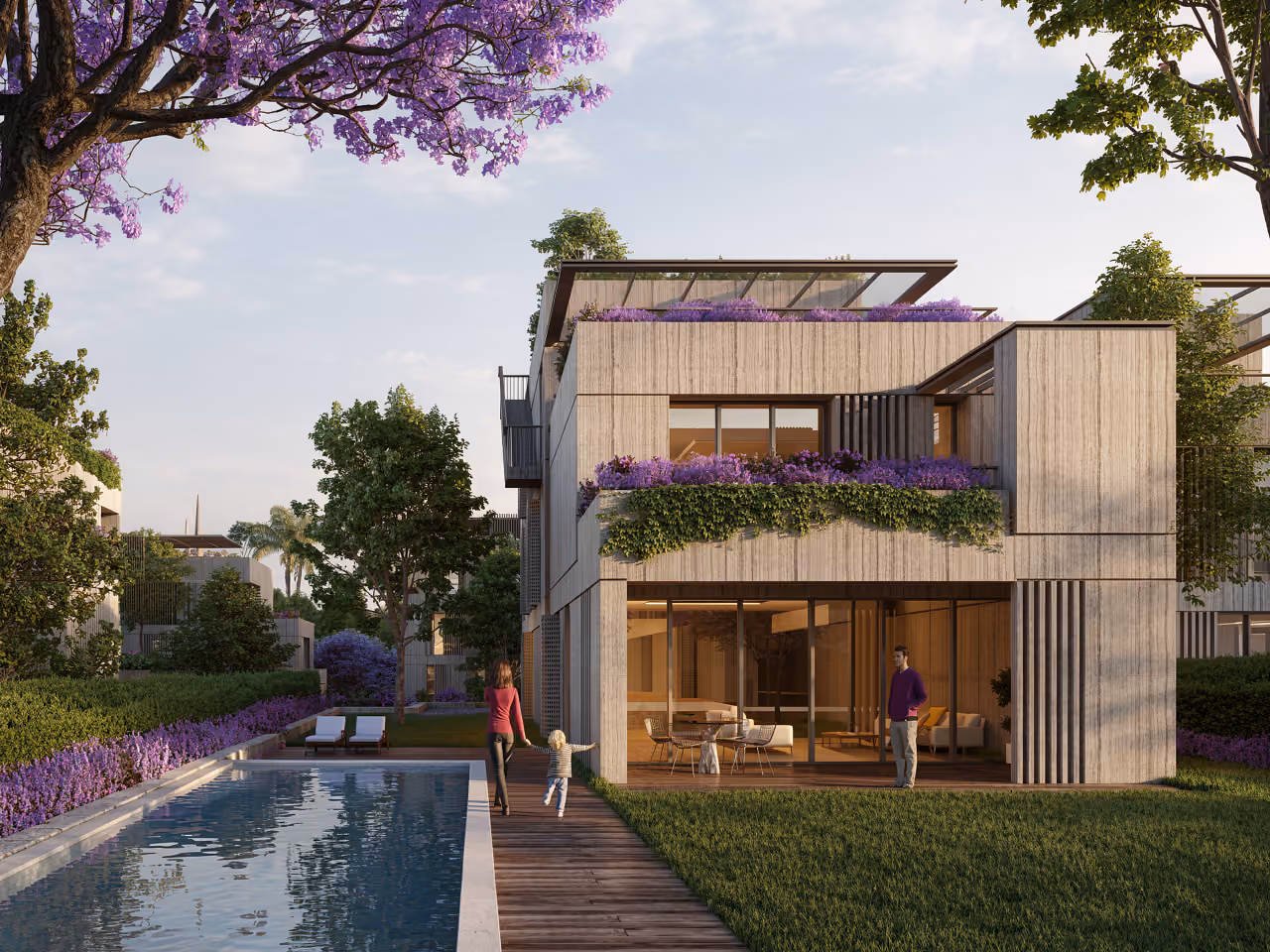 Townhouse at Bramieh Village in Bramieh, with a jacaranda tree, pool deck and lawn, residents walking past stone-clad facades with planted terraces