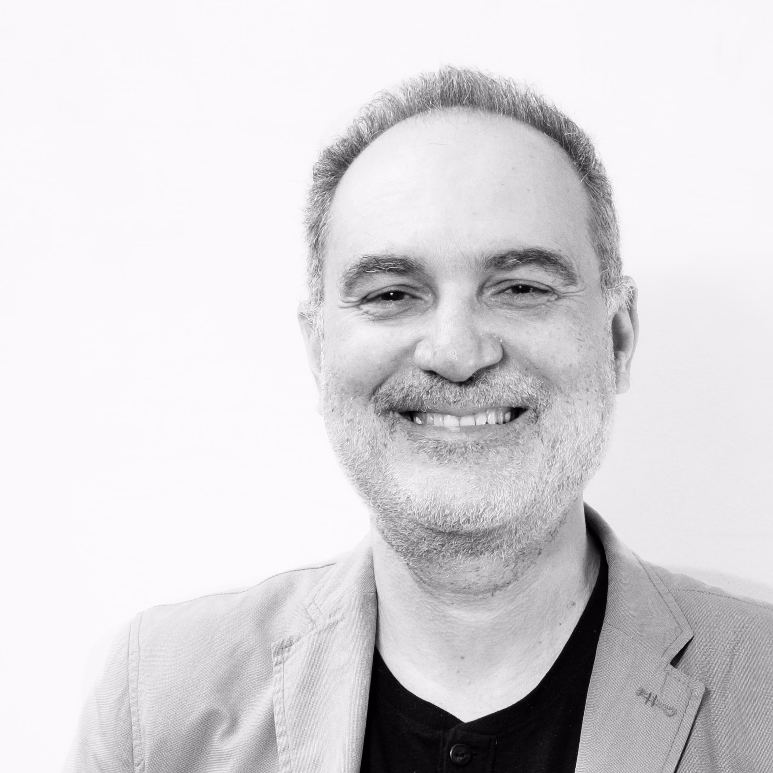 Georges Hakim, Head of Development and Production at Nabil Gholam Architects, black and white portrait smiling in a light blazer over a dark shirt