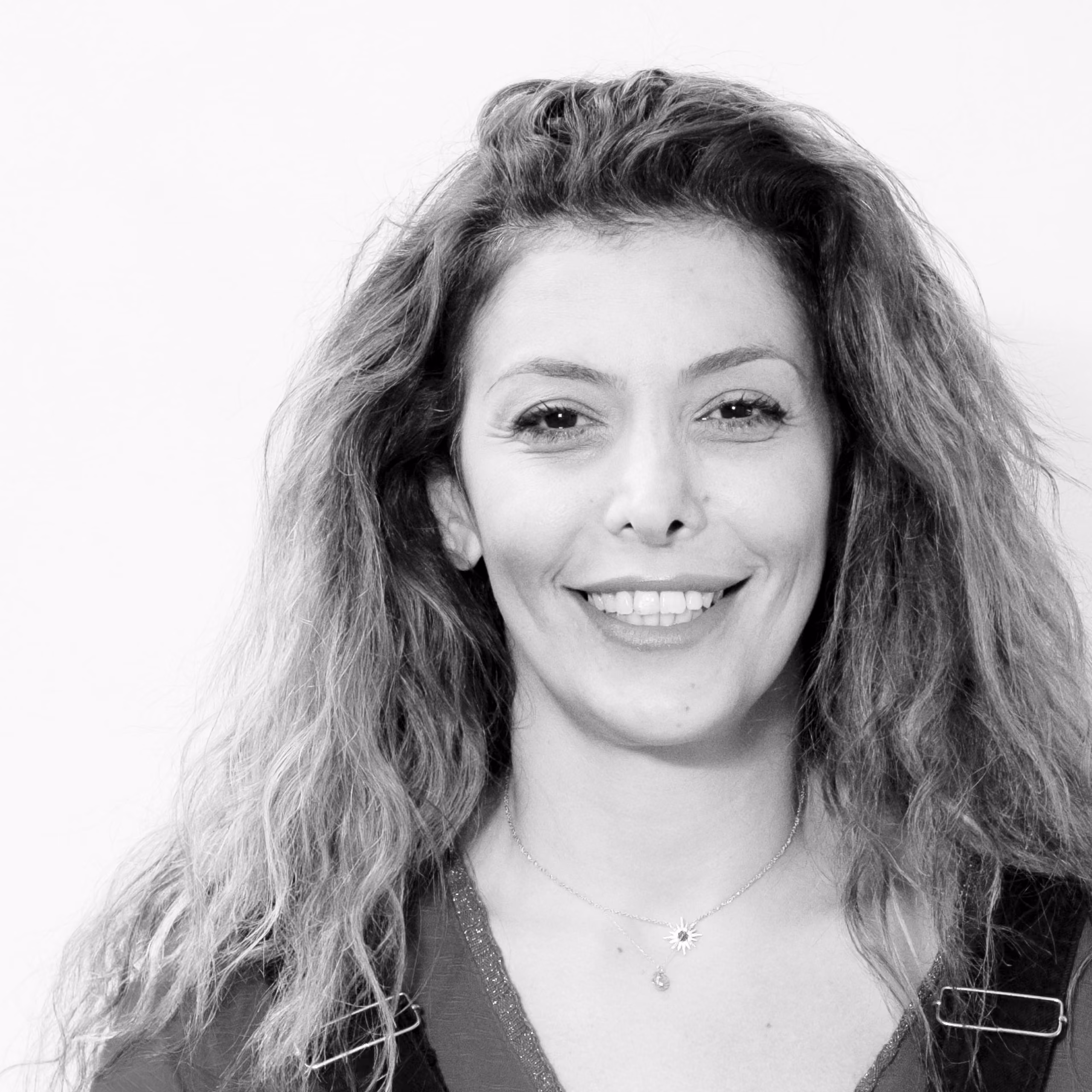 Rasha Fakhoury, Administrative Assistant at Nabil Gholam Architects, black and white portrait smiling with long curly hair and a pendant necklace