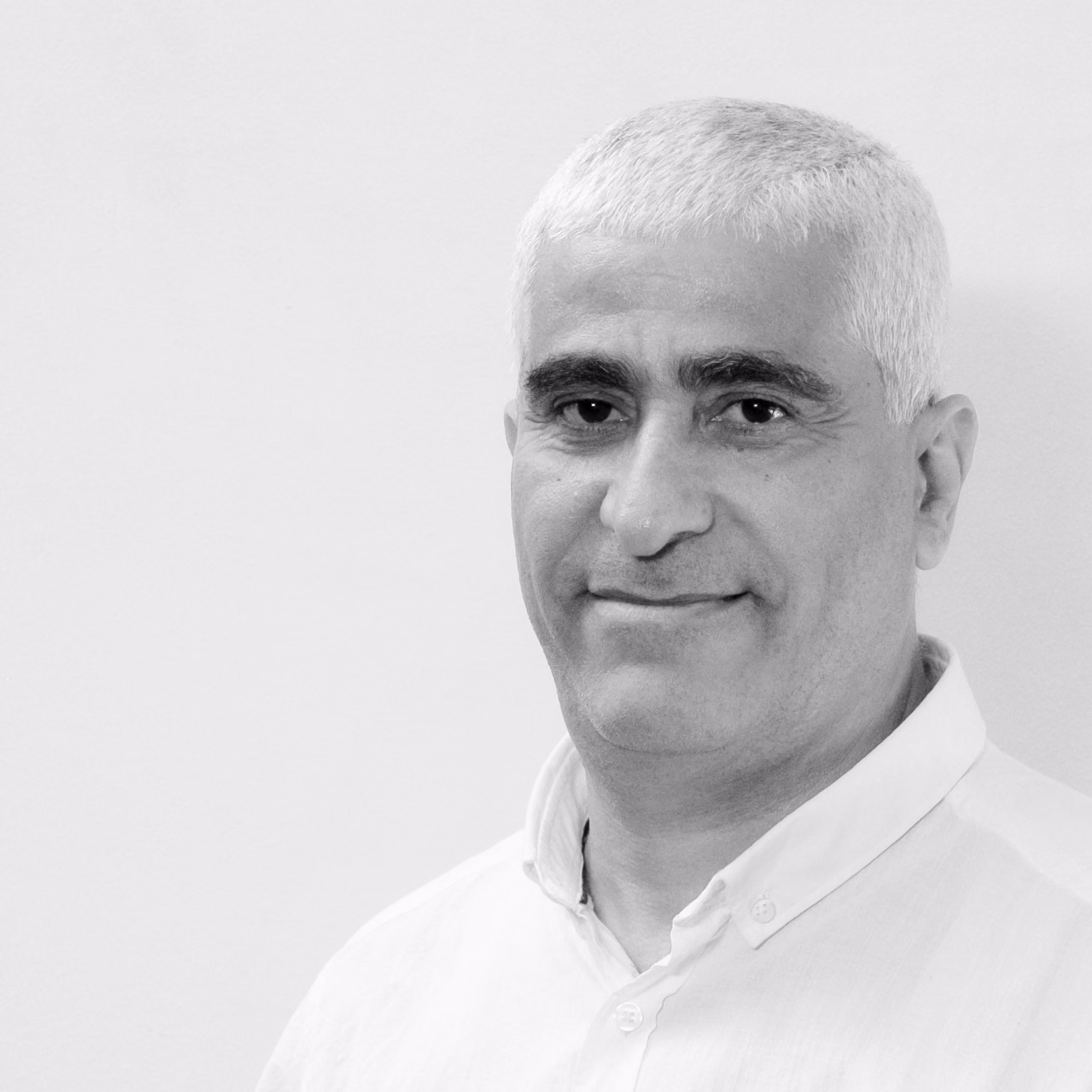 Hassan Ghamloush, Senior Interior Designer at Nabil Gholam Architects, black and white portrait with short grey hair in a white buttoned shirt
