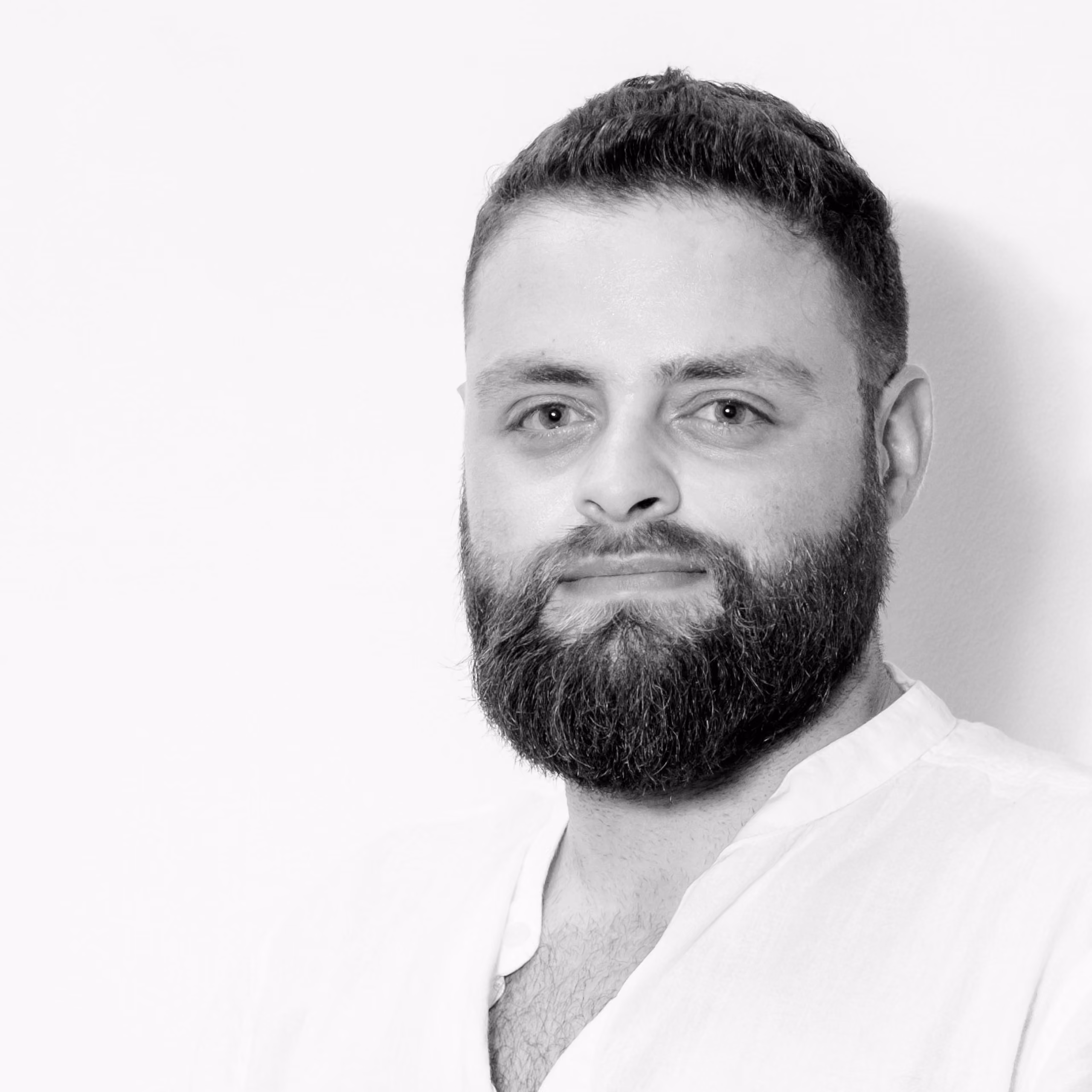 Hanna Nassar, Architect at Nabil Gholam Architects, black and white portrait with a full beard wearing an open-collar white shirt