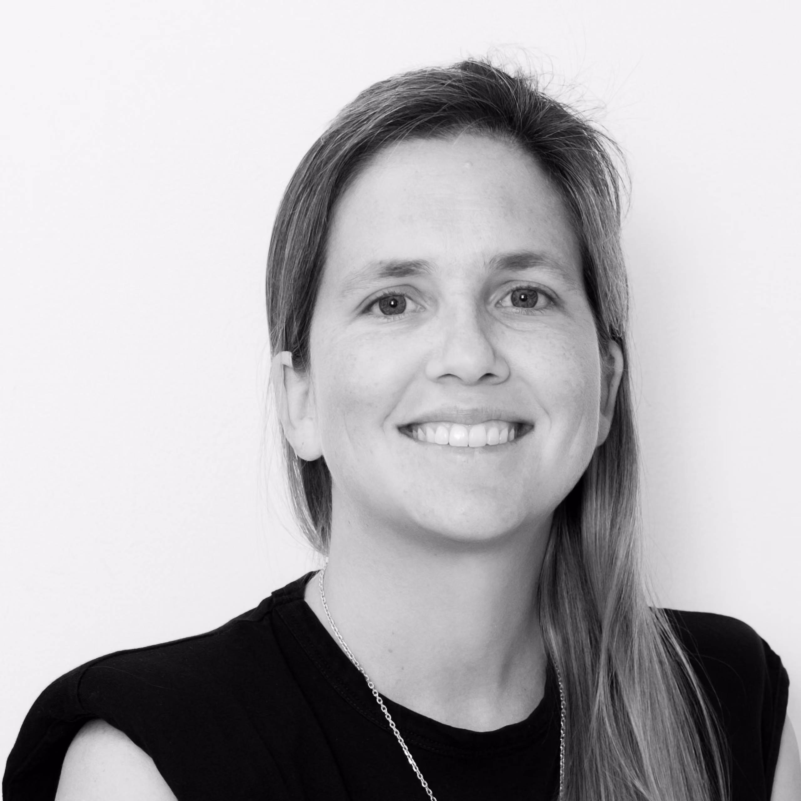 Isabel Pablo Romero, Senior Architect at Nabil Gholam Architects, black and white portrait smiling with long hair and a sleeveless top