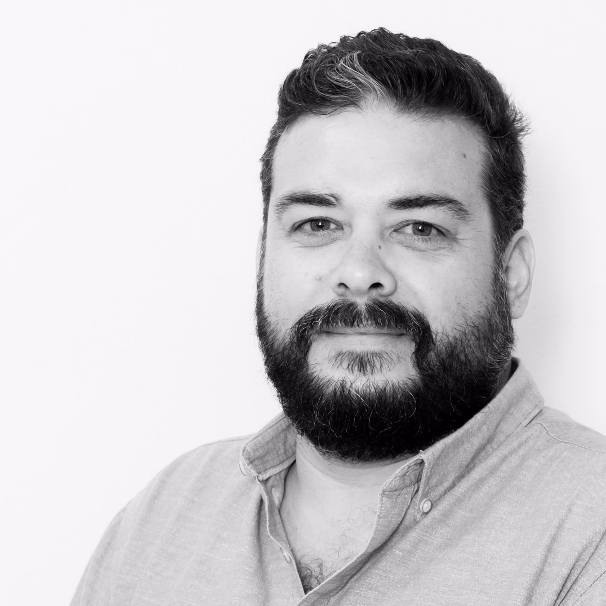 Ismael Páez, Senior Architect at Nabil Gholam Architects, black and white portrait with a beard and buttoned collared shirt