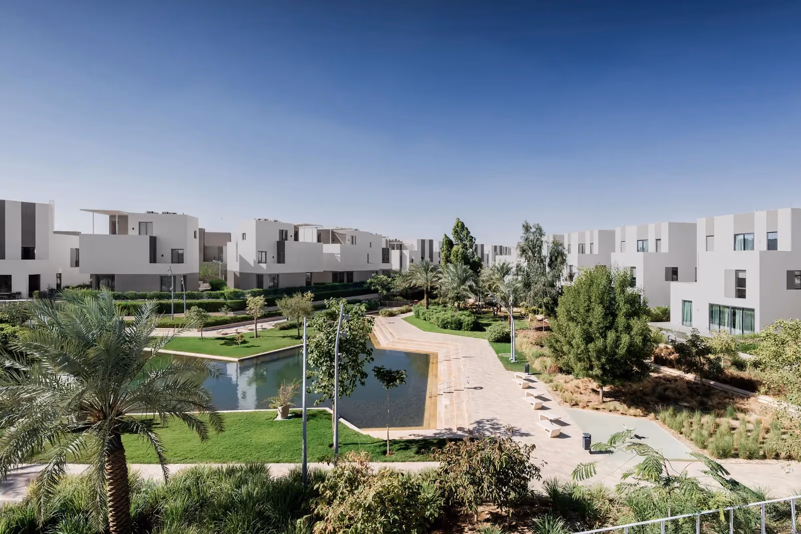 Qortuba Oasis, a low-rise residential compound by Nabil Gholam Architects, with white villas overlooking a landscaped garden and reflecting pool in Riyadh, Saudi Arabia