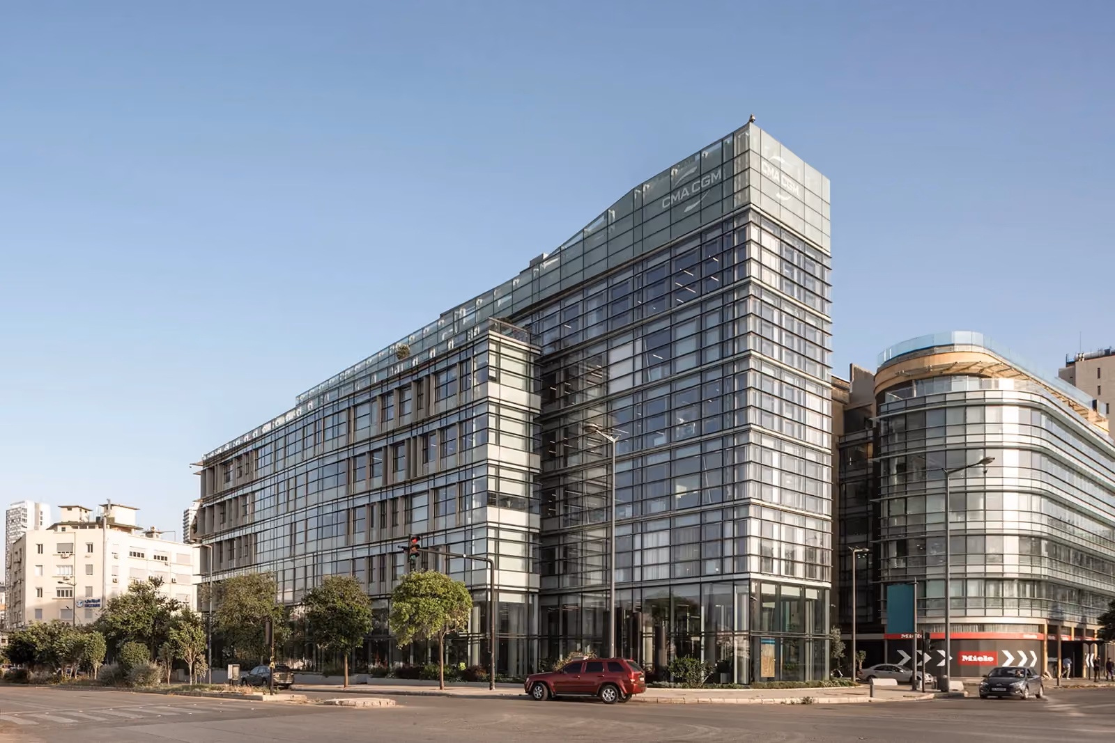 CMA-CGM Headquarters Refurbishment by Nabil Gholam Architects, a sloped glass-clad office tower with angular tapered roofline on a busy Beirut, Lebanon street corner