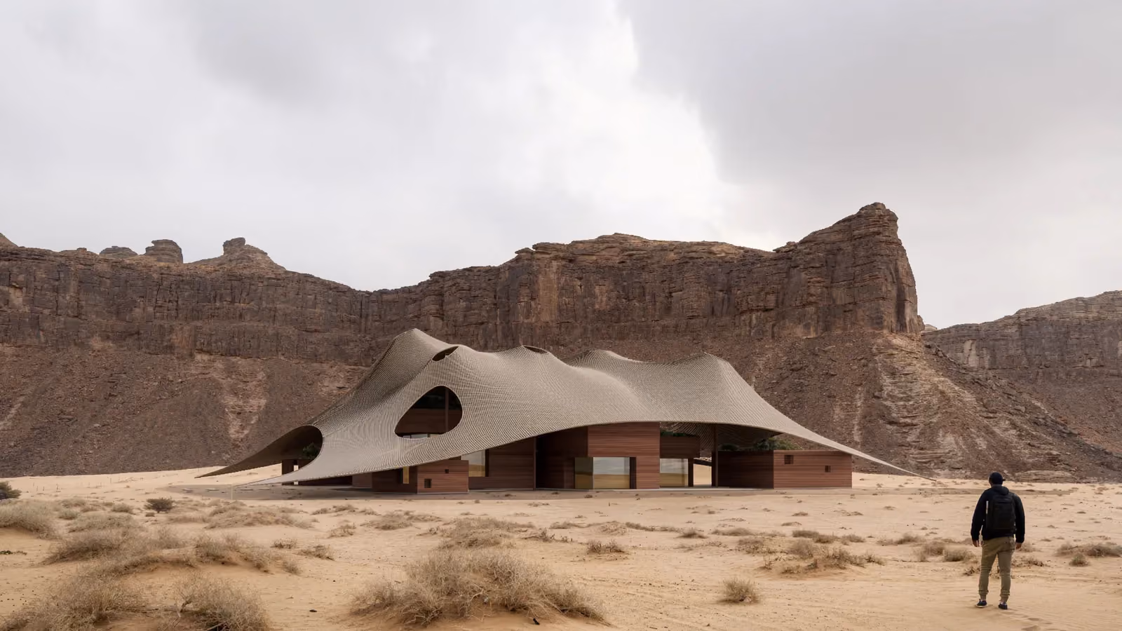 Buyut, a residential project by Nabil Gholam Architects with a wave-like perforated canopy over timber-clad volumes, set among sandstone cliffs in Al Ula, Saudi Arabia