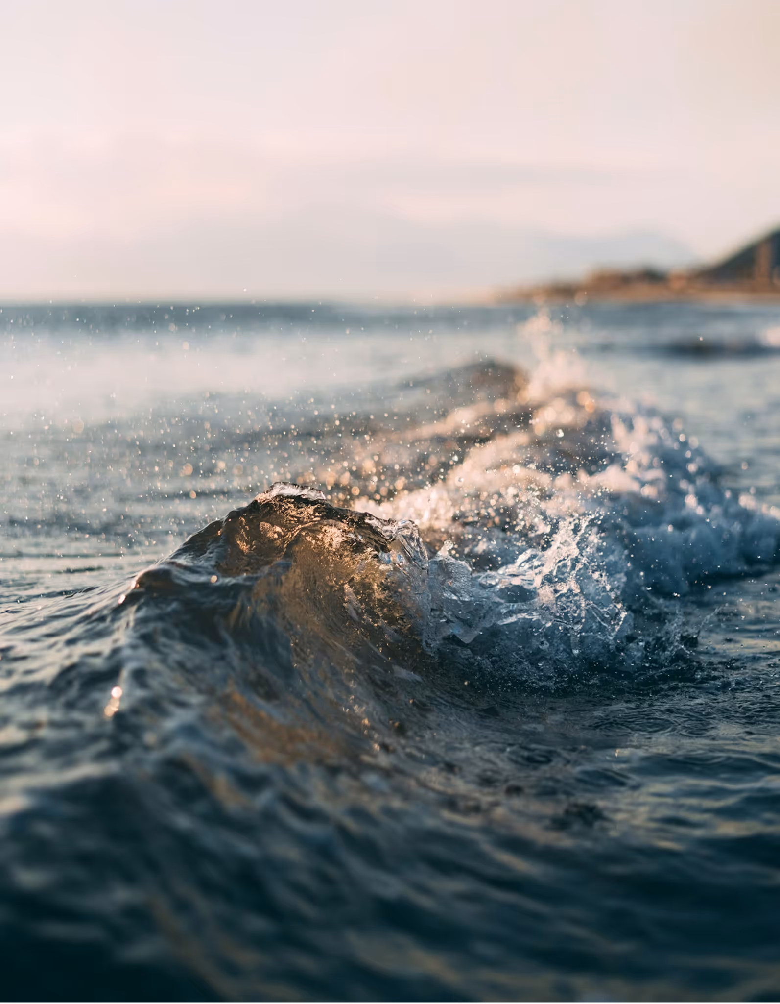 Блискуча хвиля, що розбивається, на морській поверхні при заході сонця біля узбережжя.