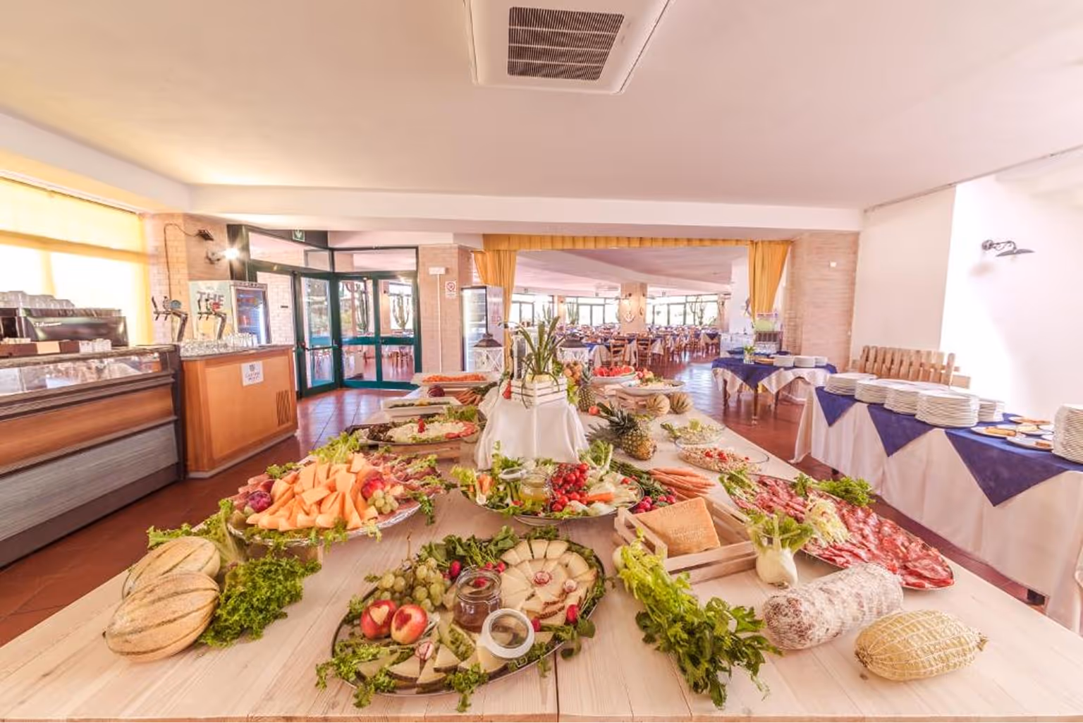 Страва шведського столу з різноманітними сирами, фруктами, овочами та м’ясними нарізками у просторій їдальні. Villaggio Mare Si