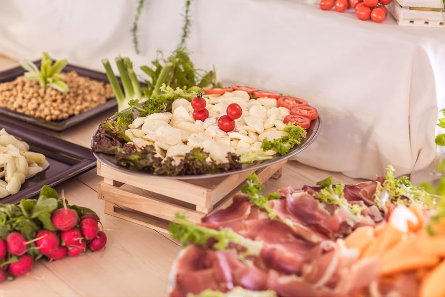 Тарілка з нарізаними бобами, прикрашена салатом, томатами і червоними ягодами, на фоні свіжих овочів та м'яса. Villaggio Mare Si