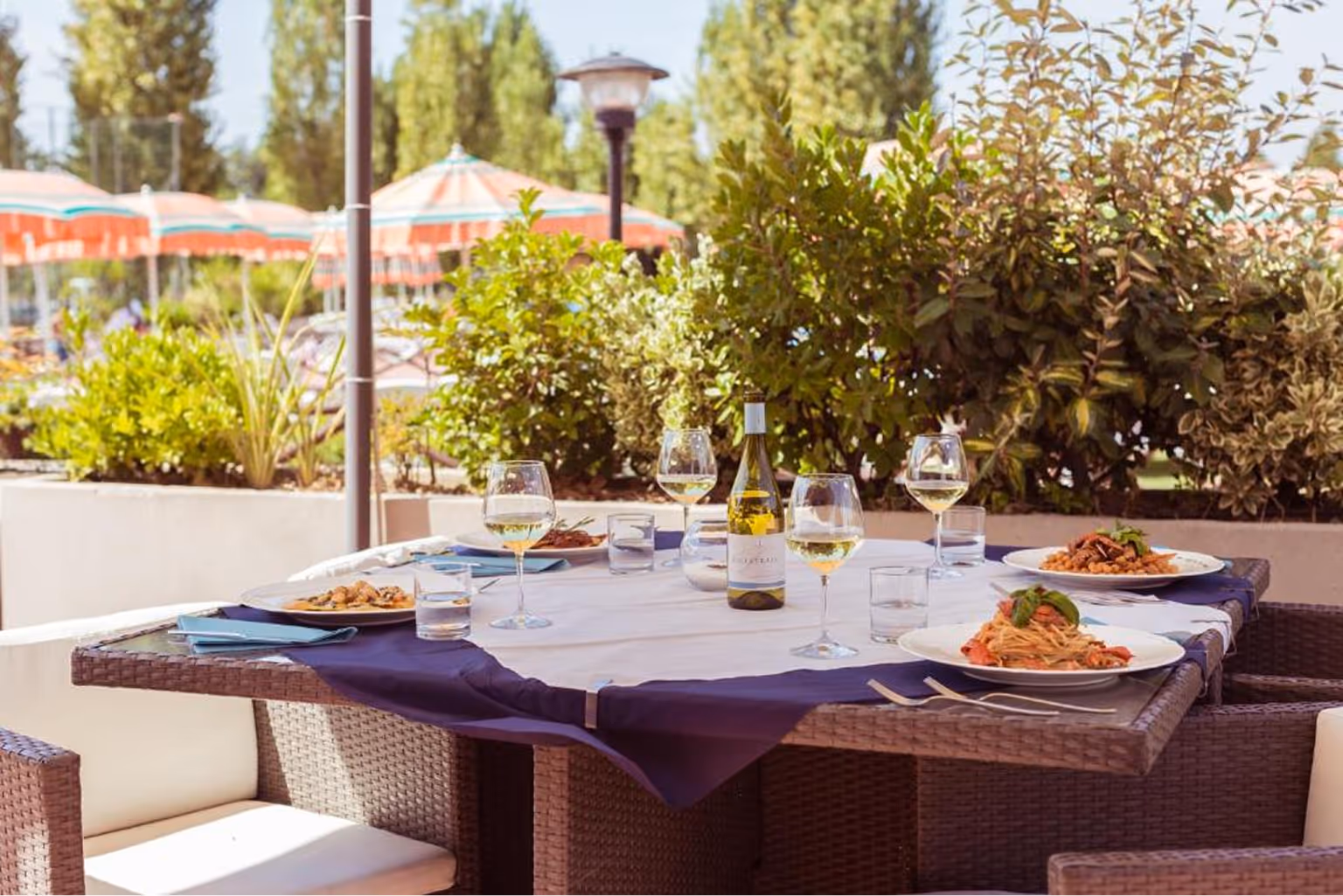 Обідній стіл на терасі з прохолодними напоями, пляшкою білого вина та тарілками з пастою. Villaggio Mare Si