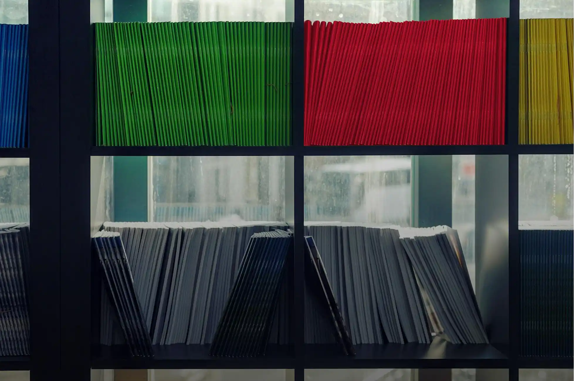 Shelves with neatly arranged documents in blue, green, red, yellow, and grayscale tones.