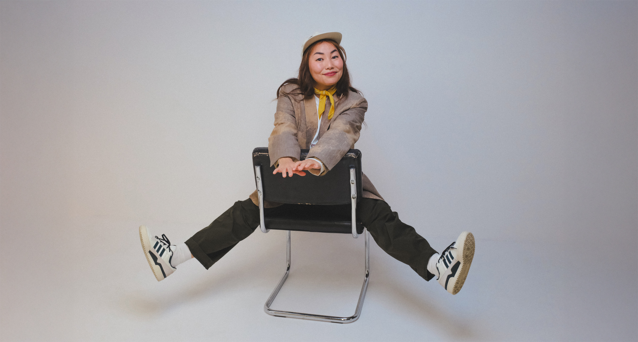 Elena sitting on a chair with her arms outstretched, smiling at the camera