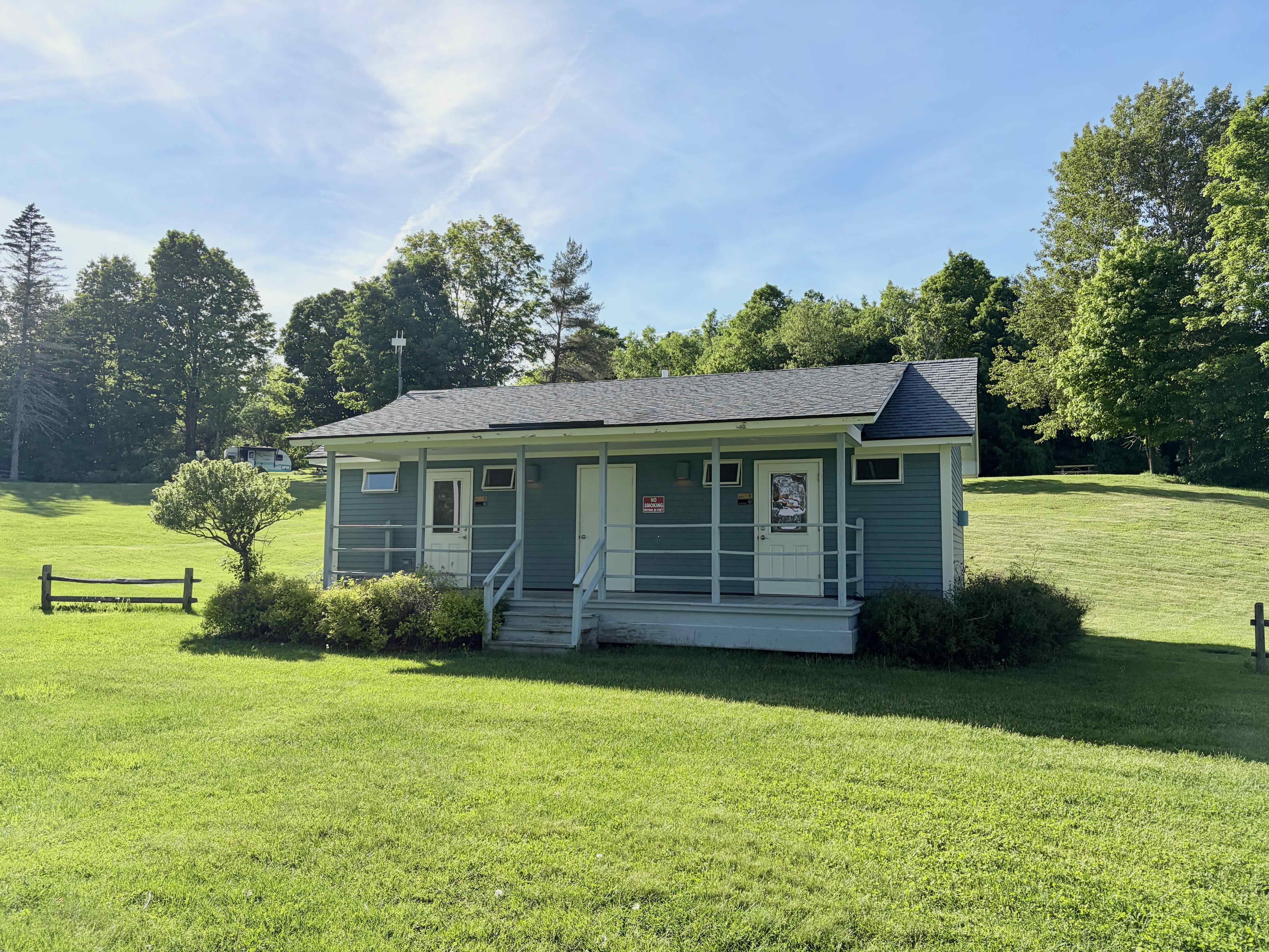 The blue bathhouse on an open lawn at Lake Champagne