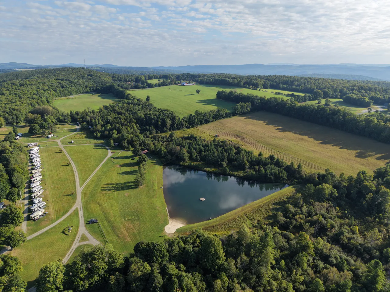 Wide aerial view of Lake Champagne, the campground, RV sites, and the surrounding Vermont landscape