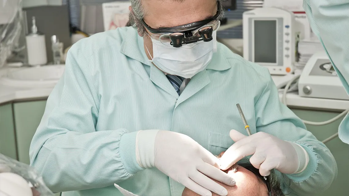 Dentist wearing protective glasses and mask working on a patient in a dental clinic.