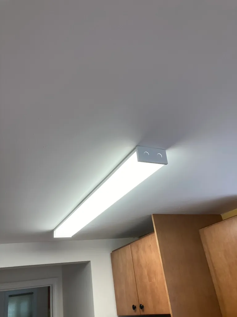 Bright rectangular ceiling light fixture above wooden kitchen cabinets.
