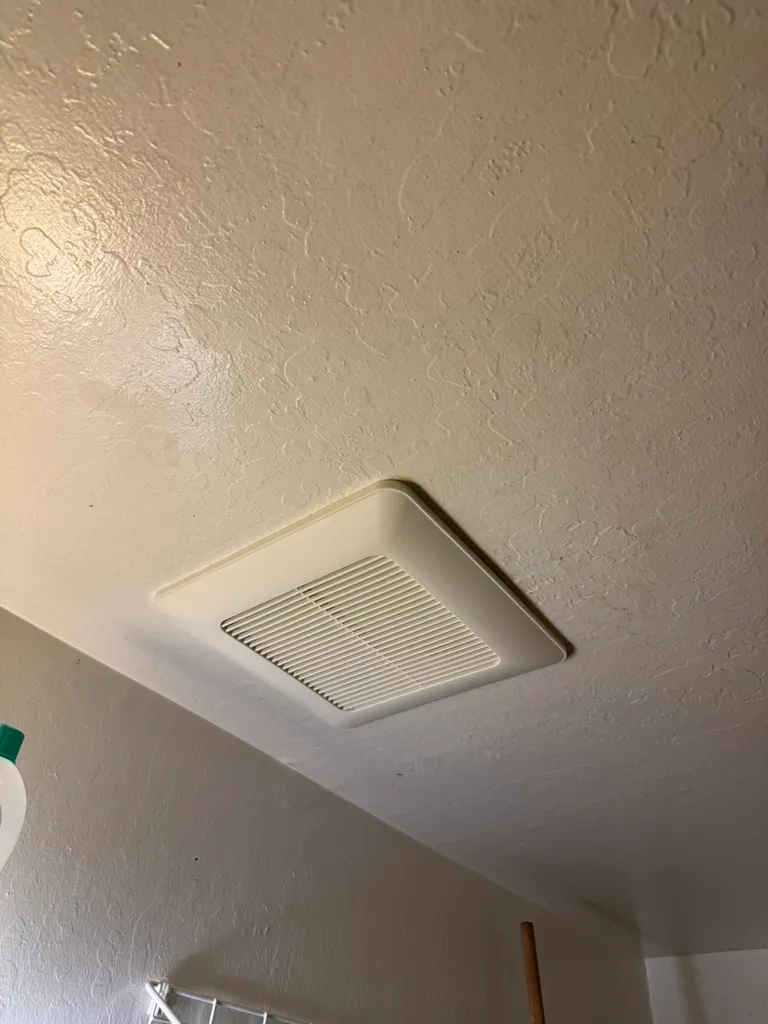 White ceiling vent cover attached to a textured ceiling in a room.