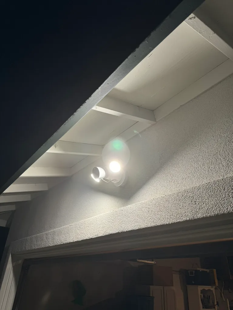 Exterior security light with two bright bulbs mounted on a white building wall at night.