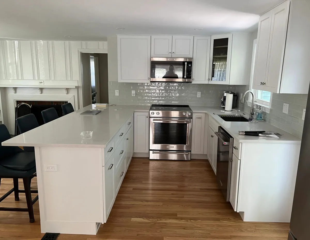 Modern kitchen with white cabinets, stainless steel appliances, hardwood floor, and a large island with stools.
