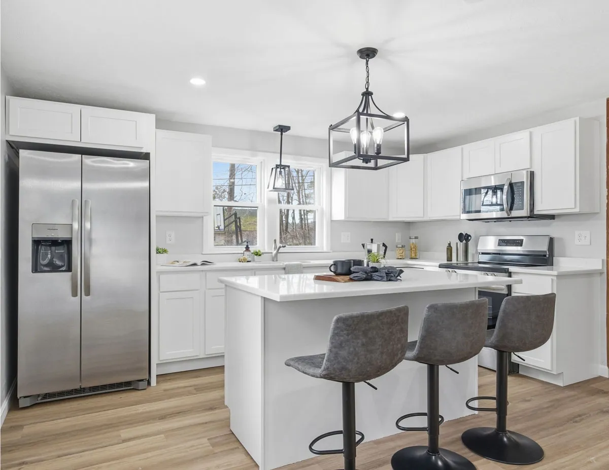 Modern kitchen with white cabinets, stainless steel appliances, a central island, and three gray bar stools.
