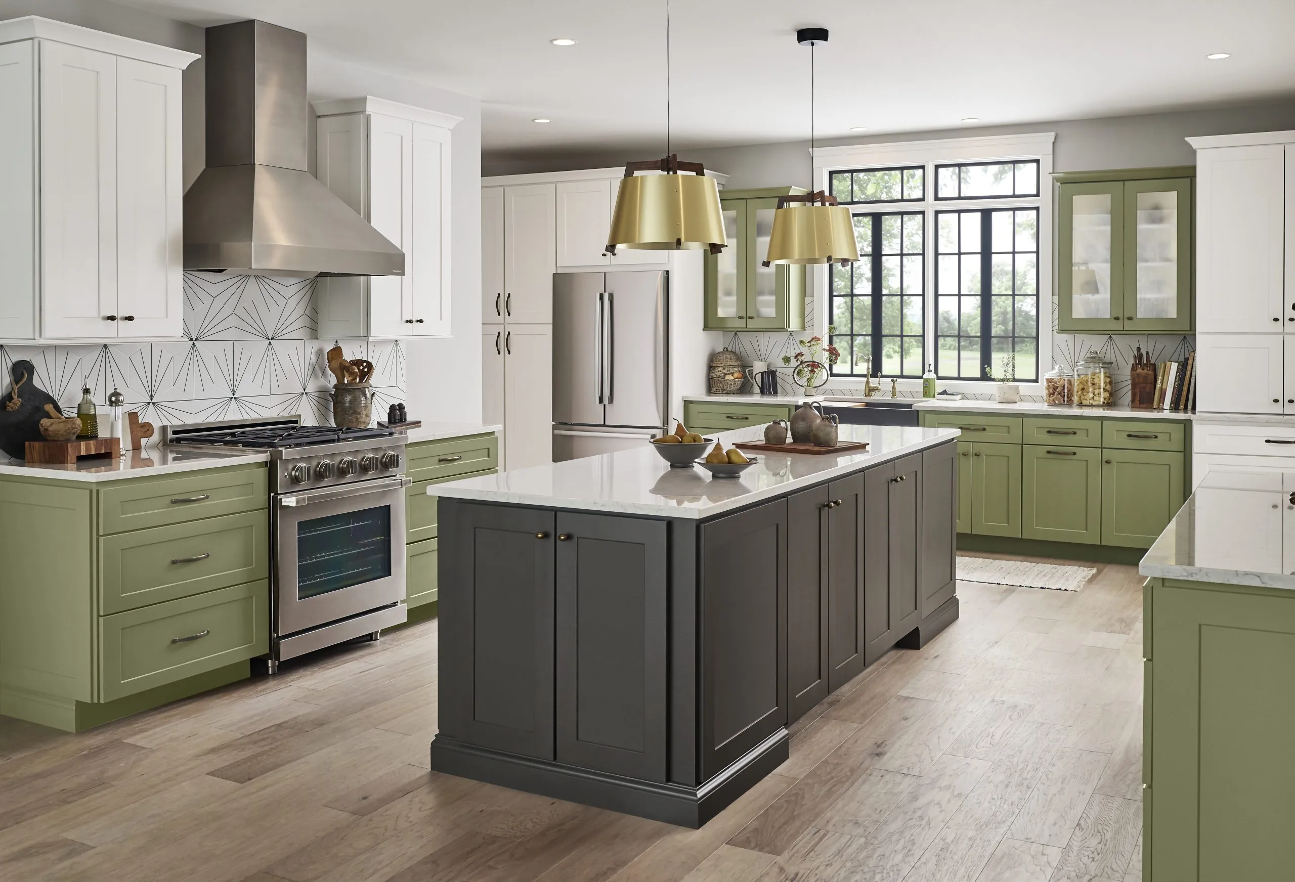 Modern kitchen with green and white cabinets, gray island, stainless stove, and large window.