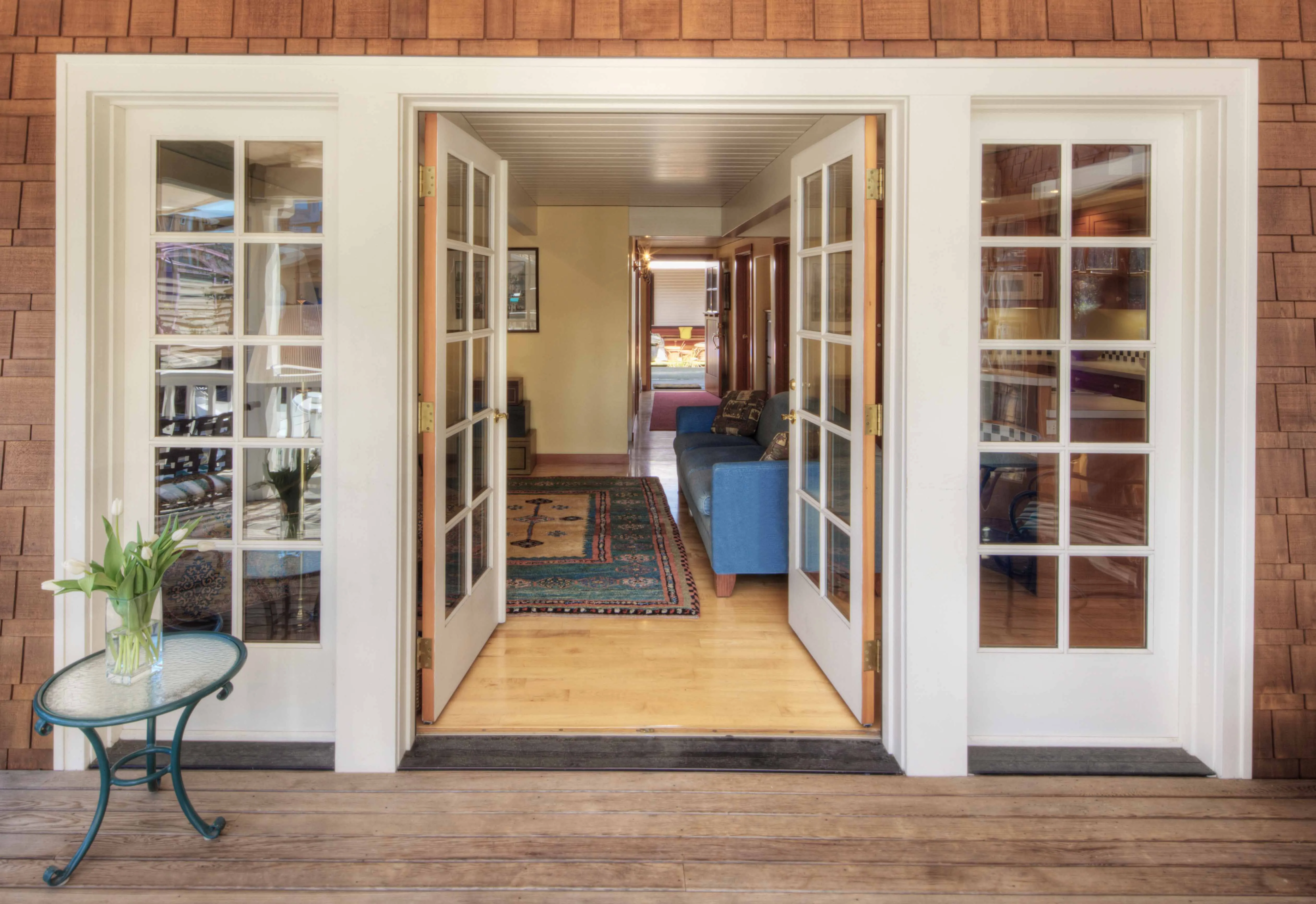 Open glass-paneled double doors leading into a room with a blue sofa and a patterned rug.