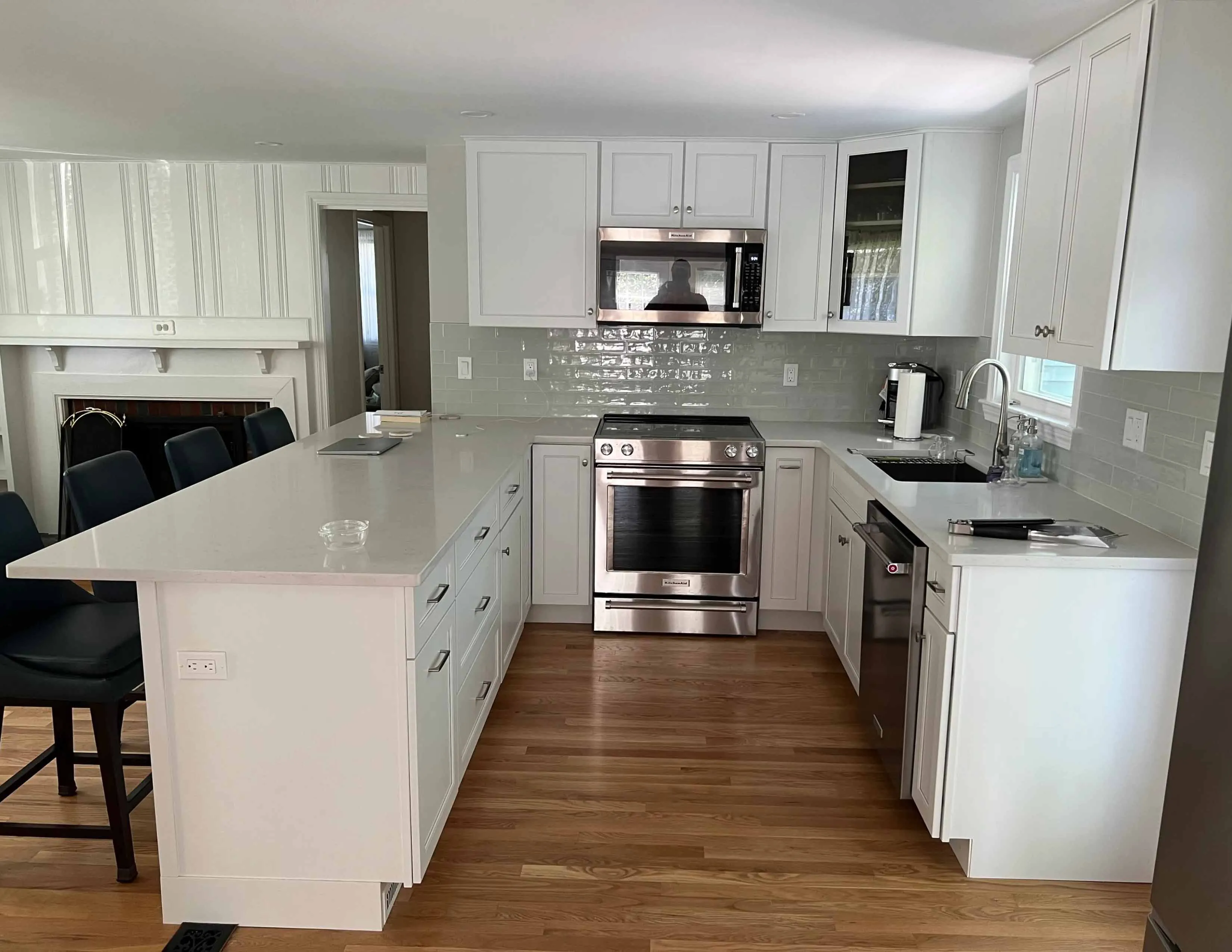 Modern kitchen with white cabinets, stainless steel appliances, L-shaped counter, and light wood floor.