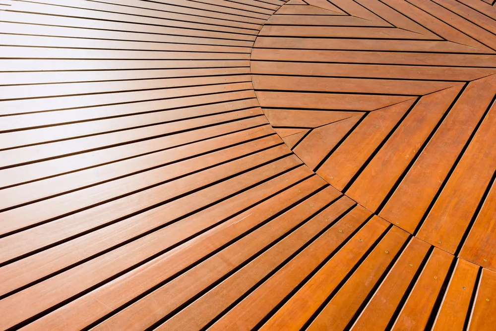 Wooden deck with a circular pattern made of straight and angled wooden planks.
