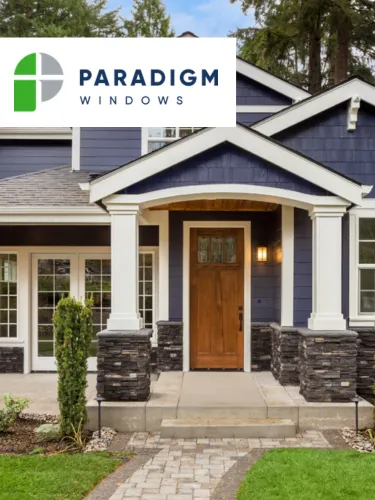 Front entrance of a blue house with white trim and a wooden door under a porch with stone pillars.