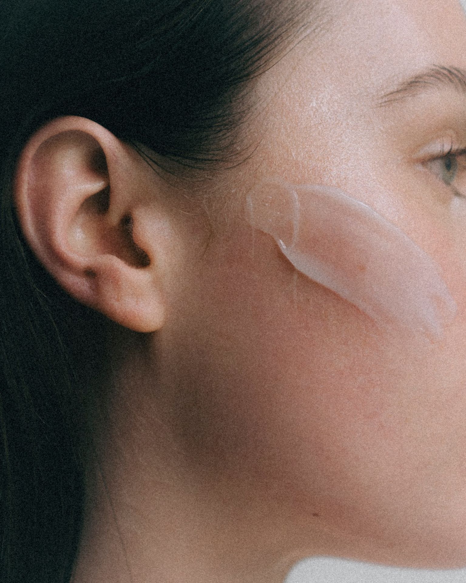 Seitliche Nahaufnahme eines Gesichts mit einer transparenten Maske auf der Wange