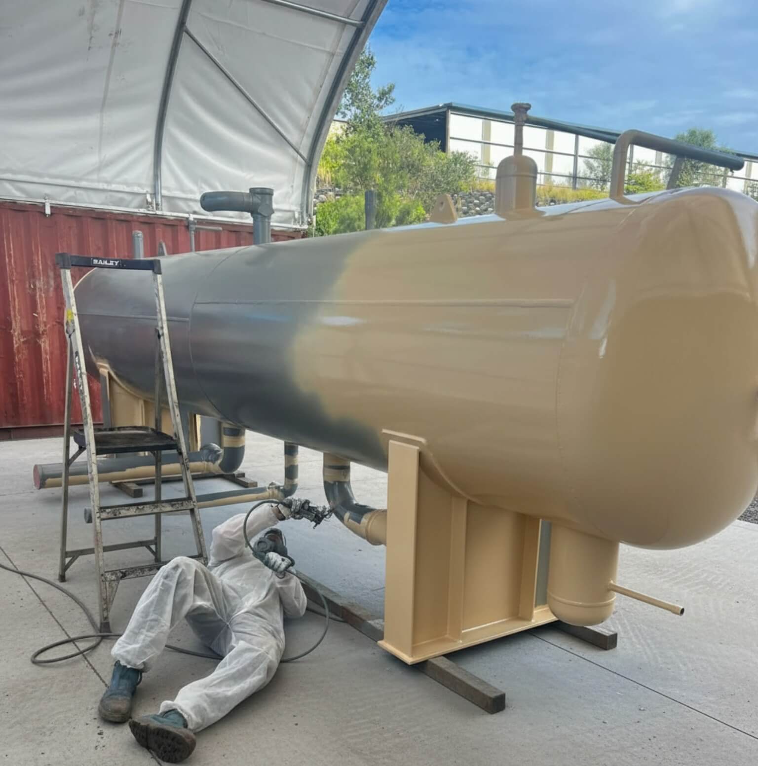 In progress: Industrial pressure vessel with technician spray-coating underside