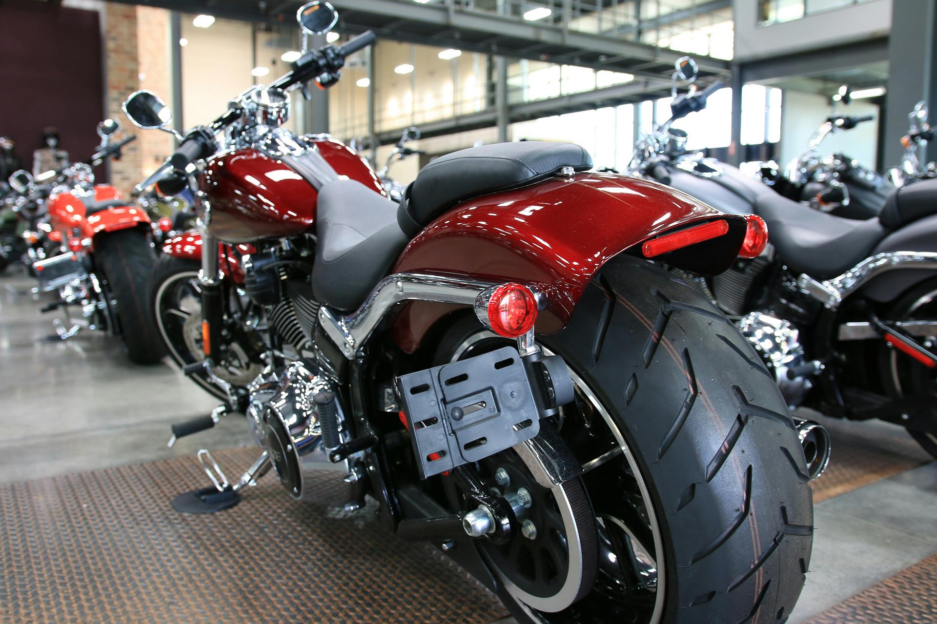 Close-up of a red motorcycle with a wide rear tire in a showroom with other motorcycles in the background.