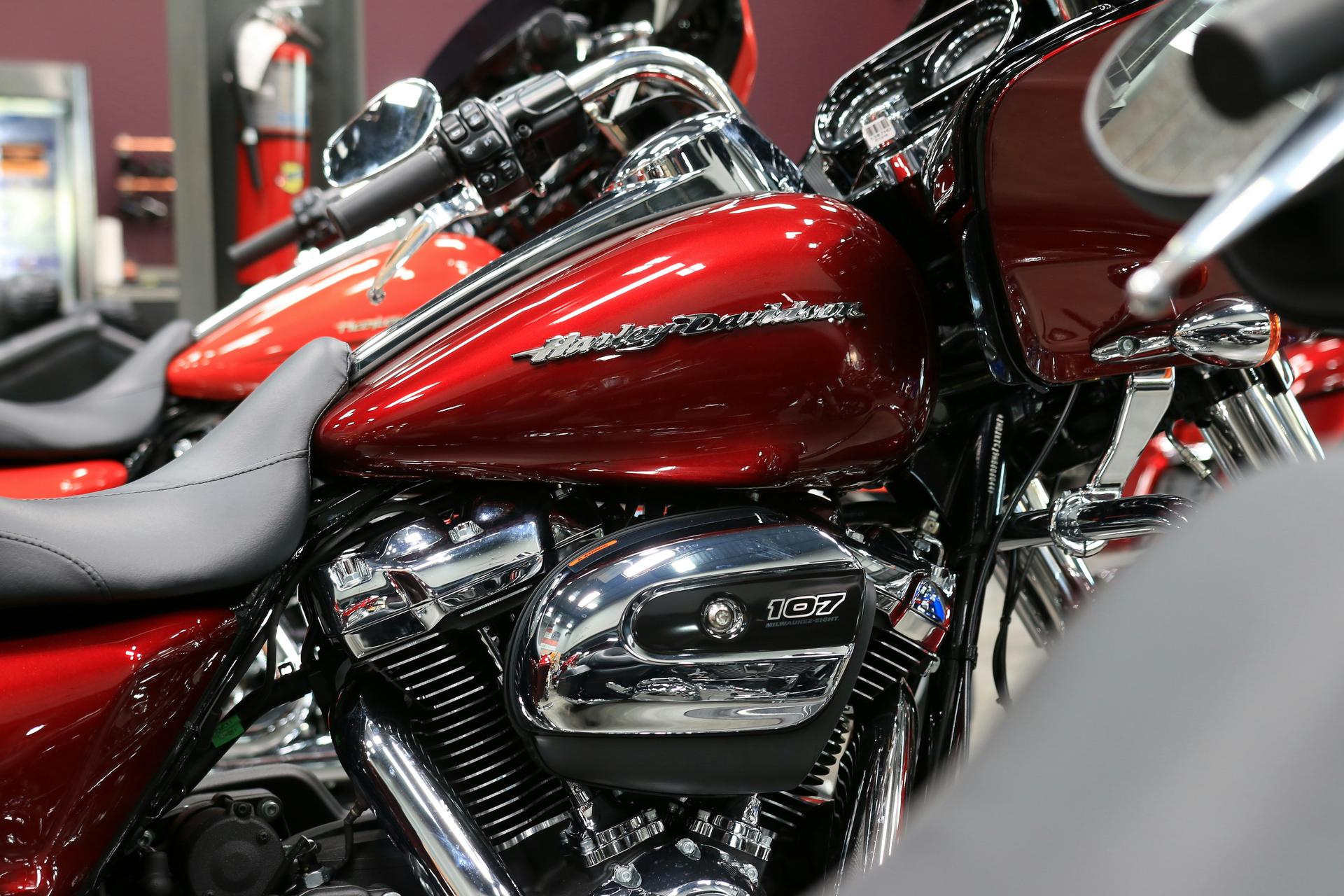 Close-up of a red Harley-Davidson motorcycle showing fuel tank, engine, and handlebar controls.
