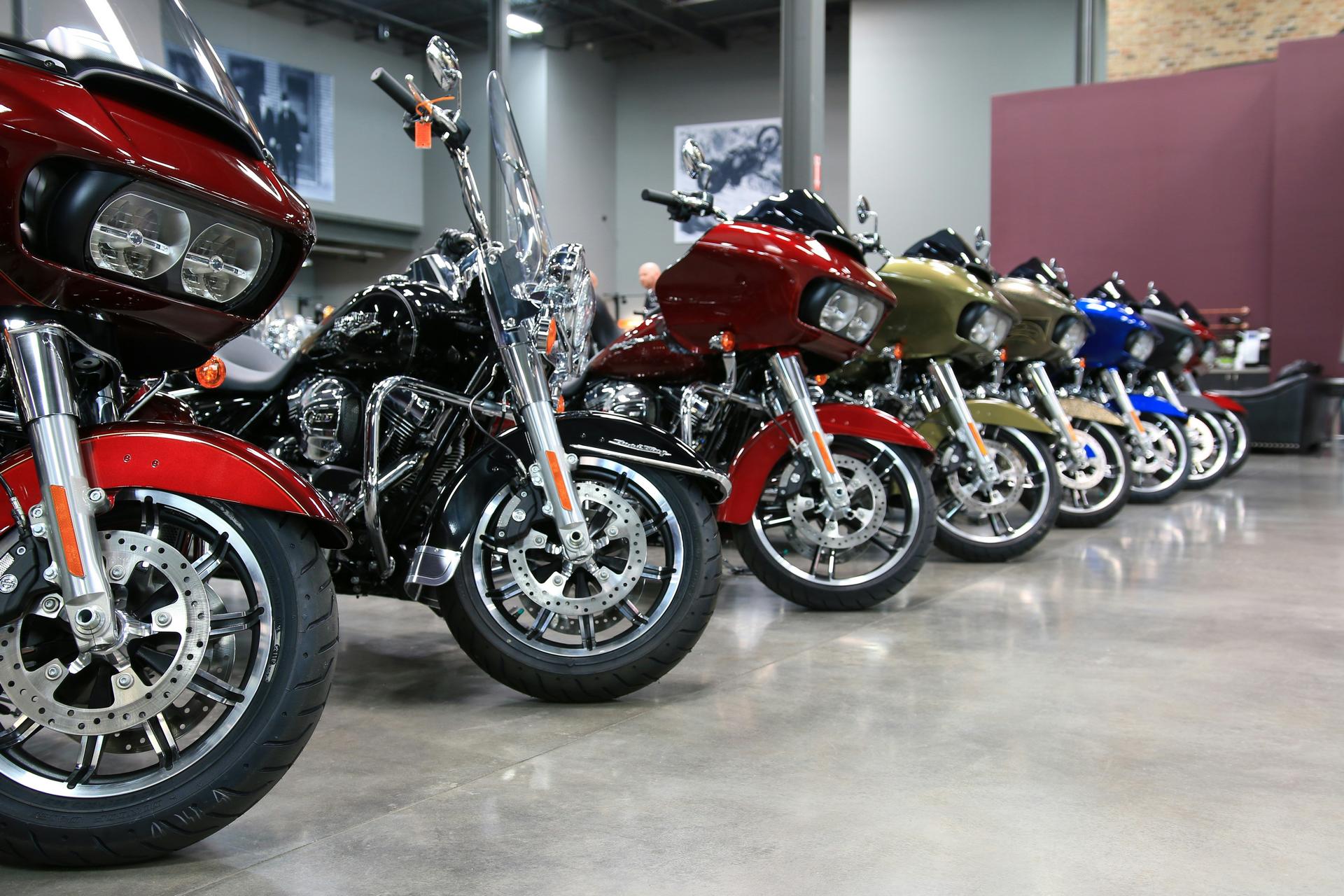 Row of colorful touring motorcycles lined up indoors on a polished concrete floor.