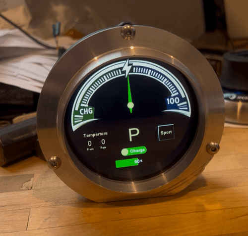 Round digital gauge displaying electric vehicle charge status at 50%, parked mode, with temperature readings of 0 for front and rear, and a sport mode indicator.