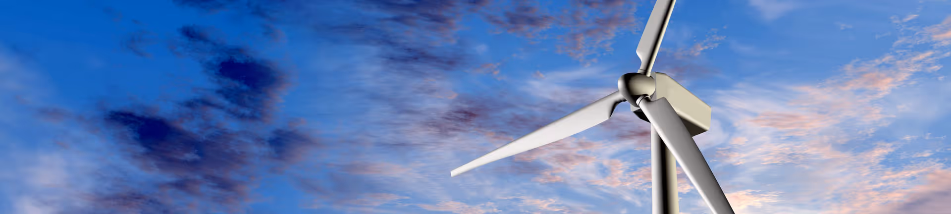 Close-up of a white wind turbine against a blue sky with scattered clouds at sunset.