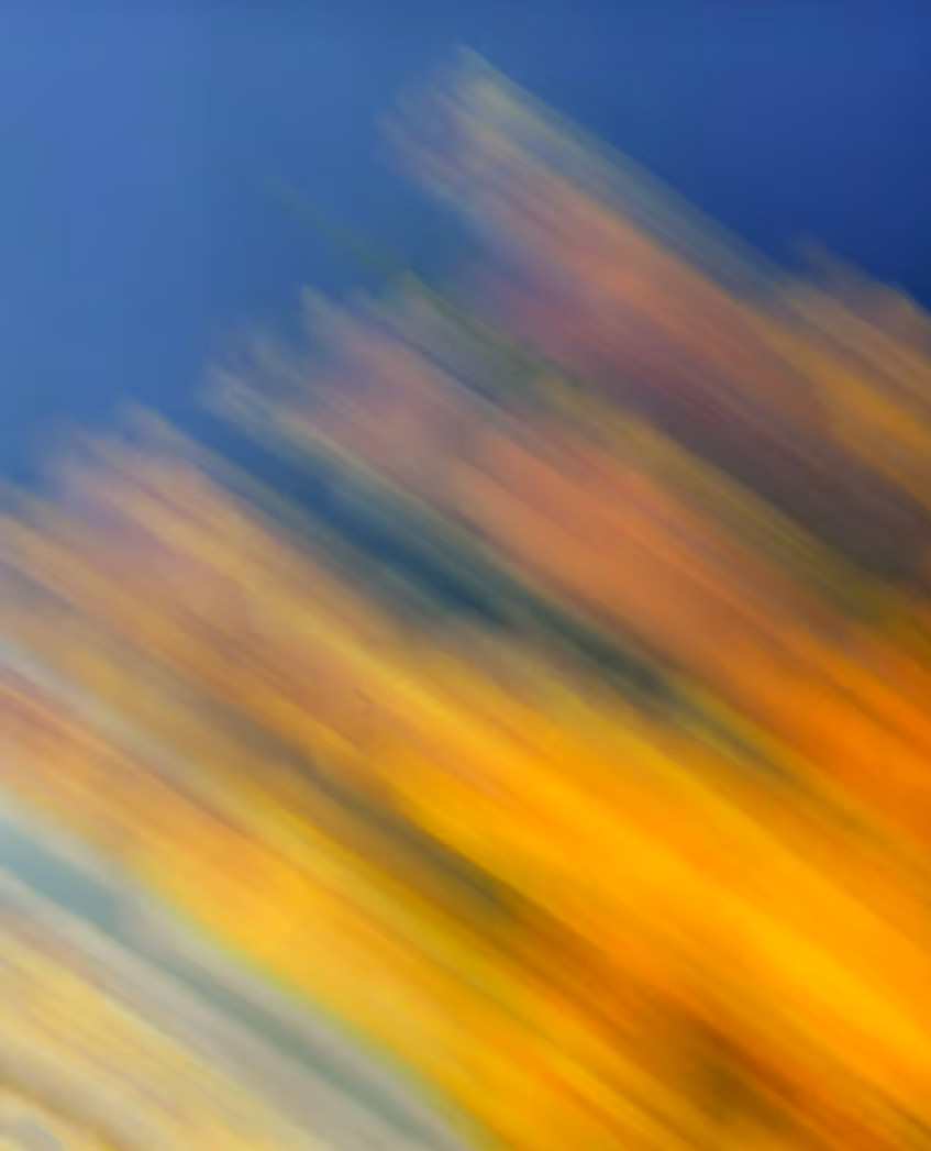 Blurred abstract blend of blue, yellow, orange, and green colors creating a dynamic motion effect.