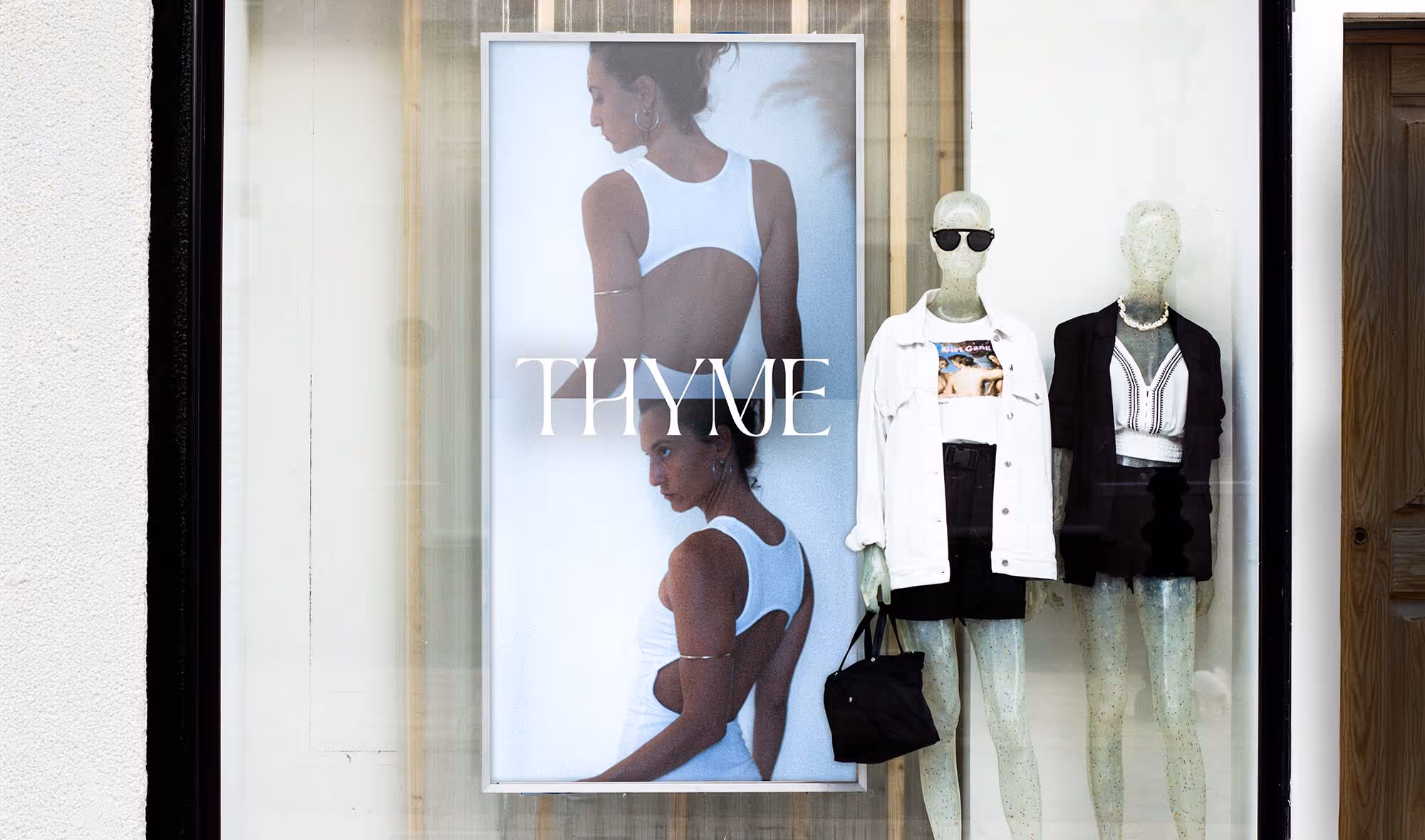 Store window with a large photo of a woman in a white dress and two mannequins dressed in black and white outfits.