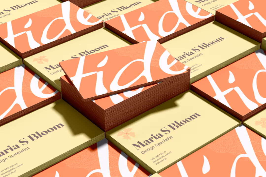Stacks of business cards for Maria S Bloom, Design Specialist, with orange and cream colors and bold text 'tide'.
