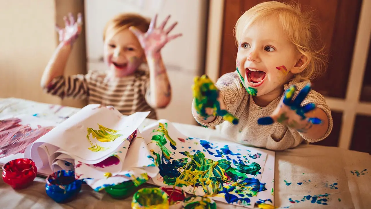 Two young children with their hands in paint.