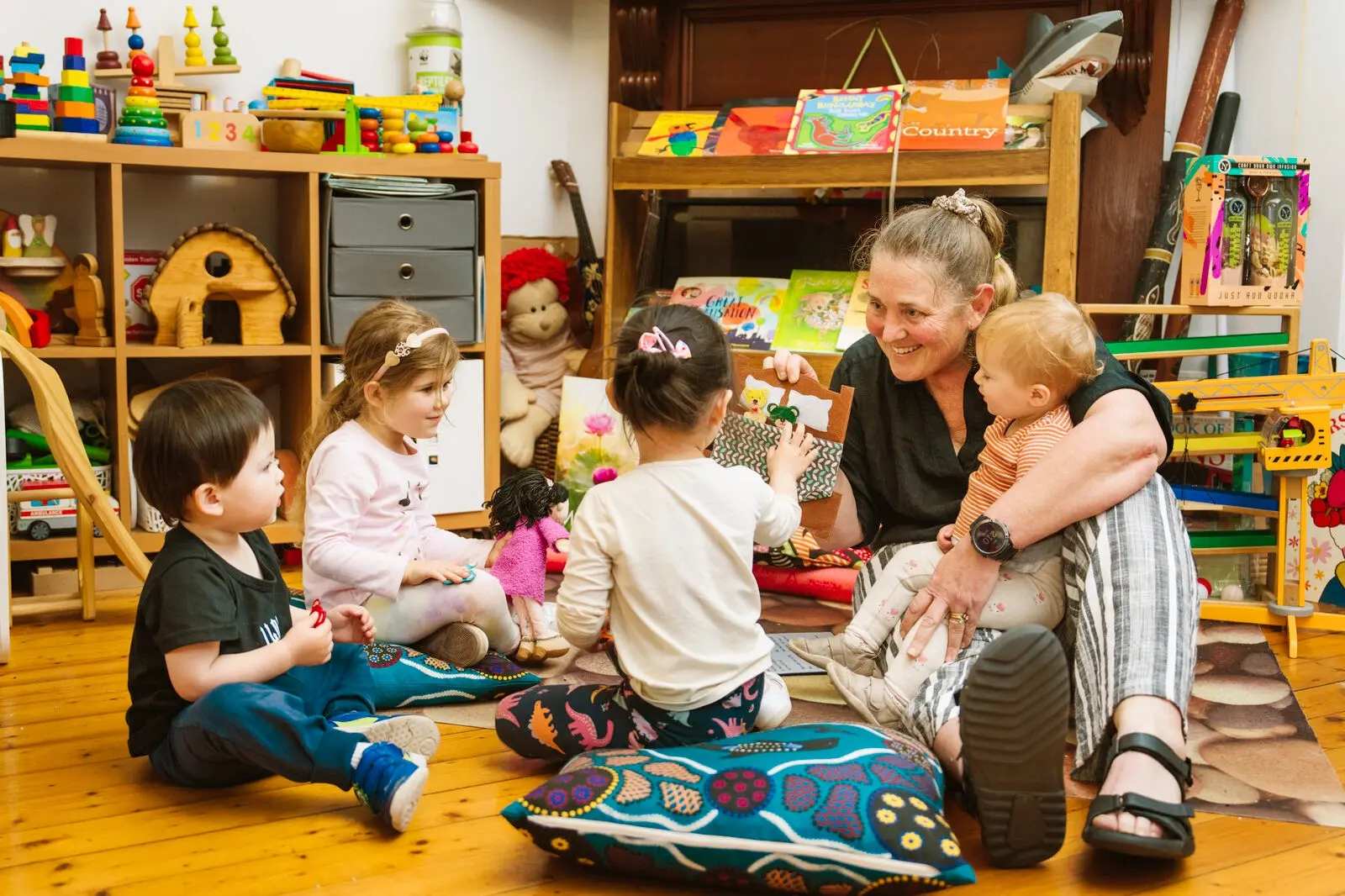 A woman sitting on the floor with a group of children.