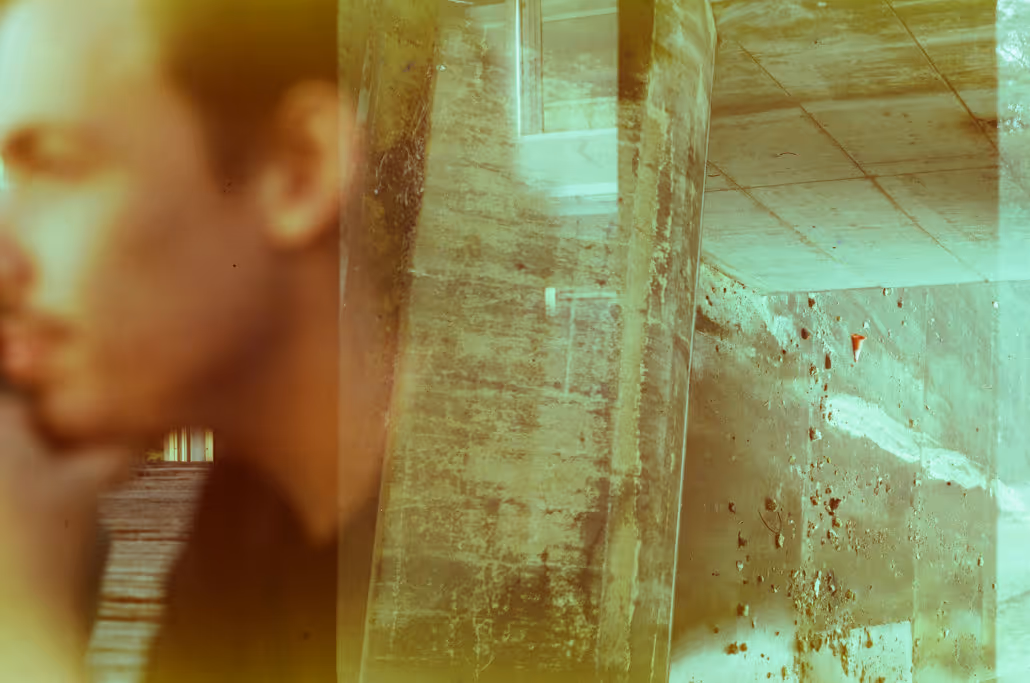 A abstract double-exposure collage featuring an out of focus face on one side overlayed with grungy concrete textures reaching across to the other side.