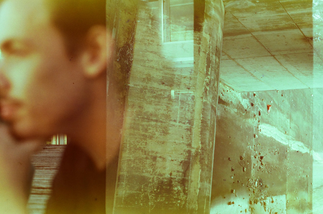 A abstract double-exposure collage featuring an out of focus face on one side overlayed with grungy concrete textures reaching across to the other side.