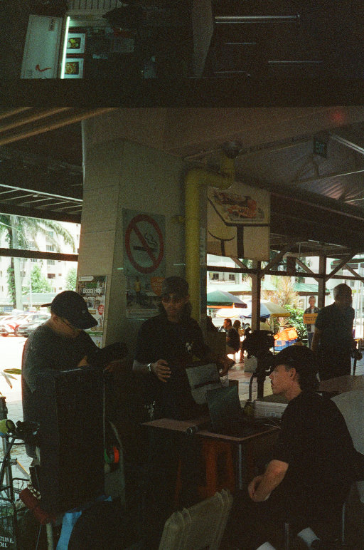 Film photo showing the crew that worked on 'Barakah', an Electus Films production, resting between takes at a hawker center in Singapore.