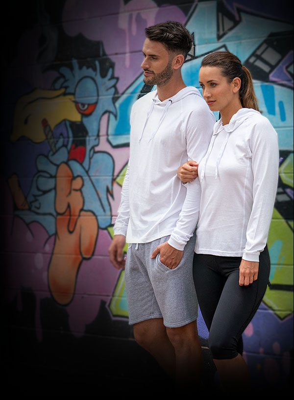 Man and woman in white hoodies standing close with a colorful graffiti wall in the background.